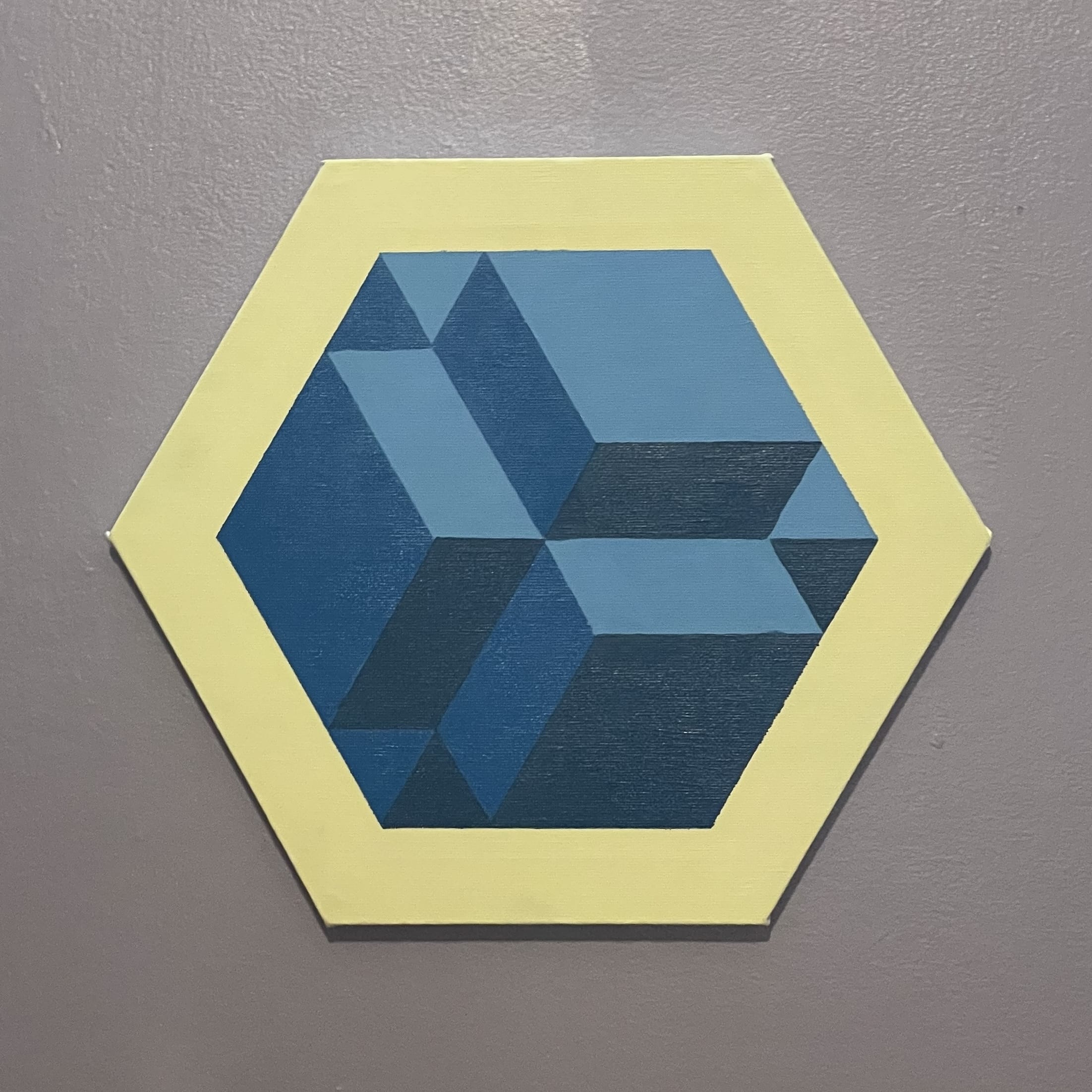 A three shade cube in blue on a yellow hexagon canvas.